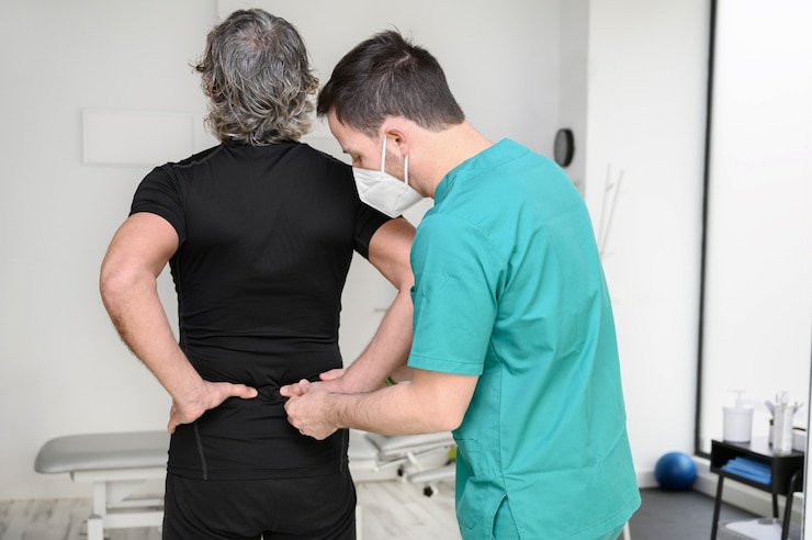 rear view physiotherapist examining man back 56854 3470