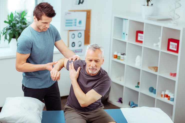 rehabilitation centre top view pleasant aged man raising his hand while having rehabilitation massage 259150 45677